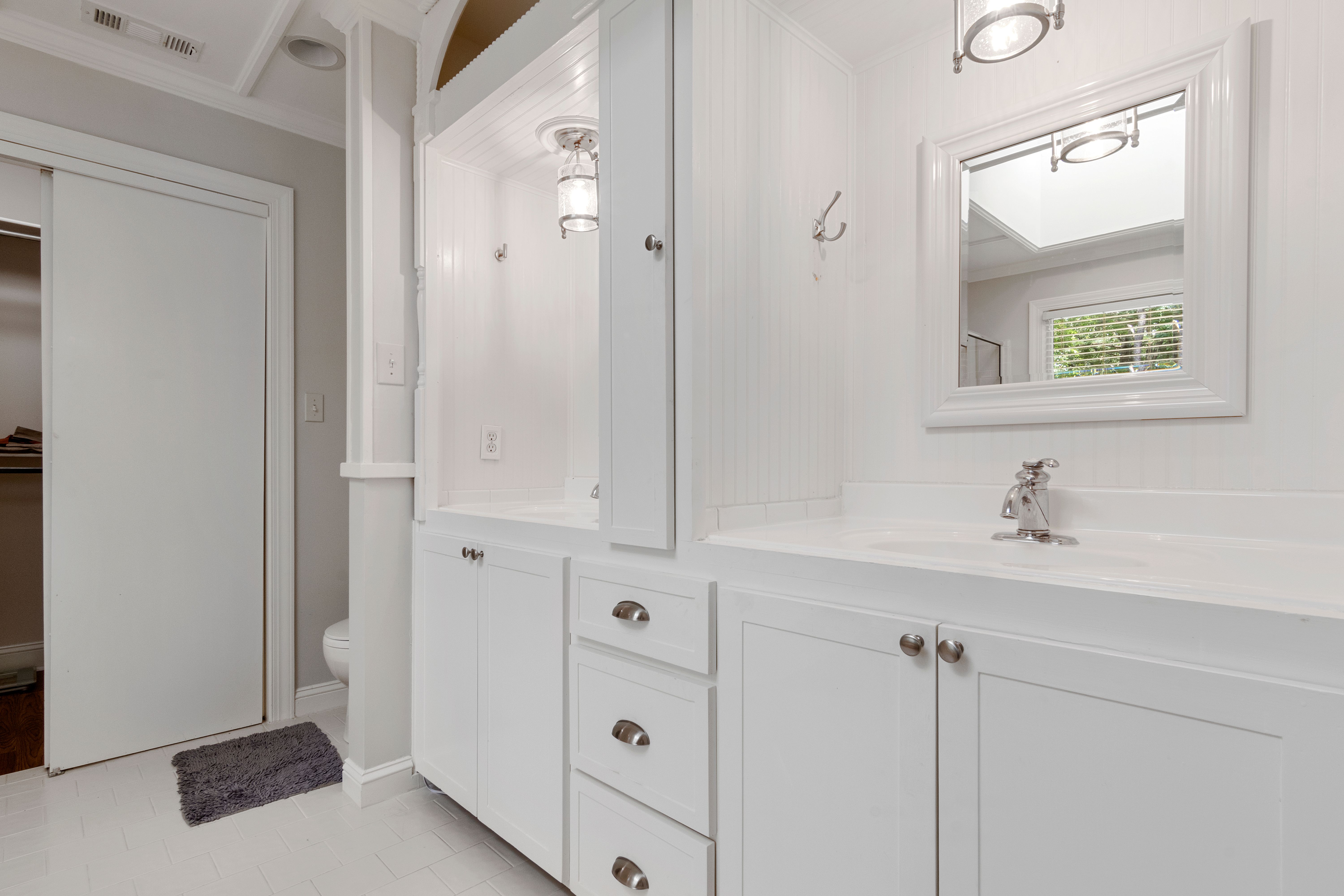 Banheiro branco elegante com móvel planejado e armários de armazenamento