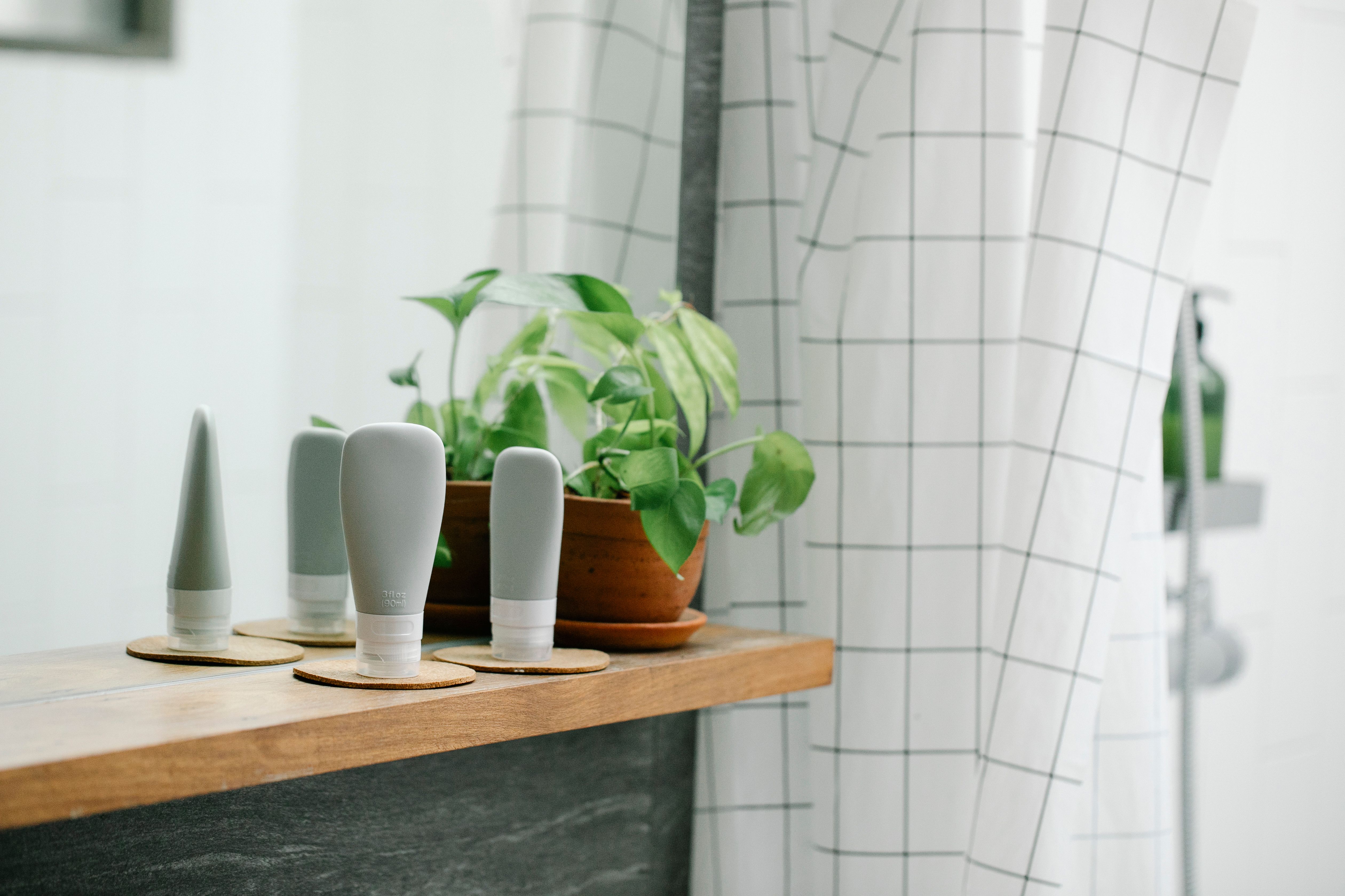 Produtos de spa em prateleira de madeira com planta e espelho ao fundo