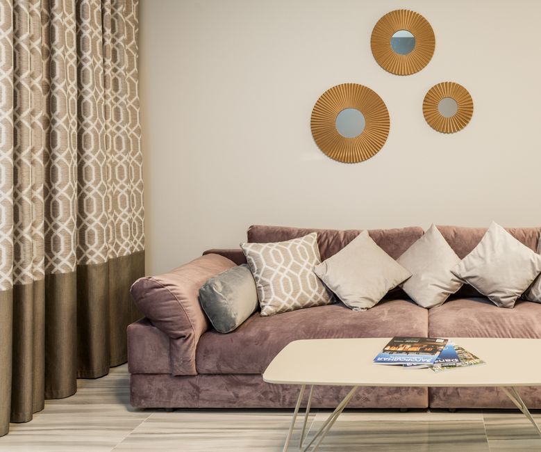 Sofá com almofadas em frente a parede decorada com espelhos