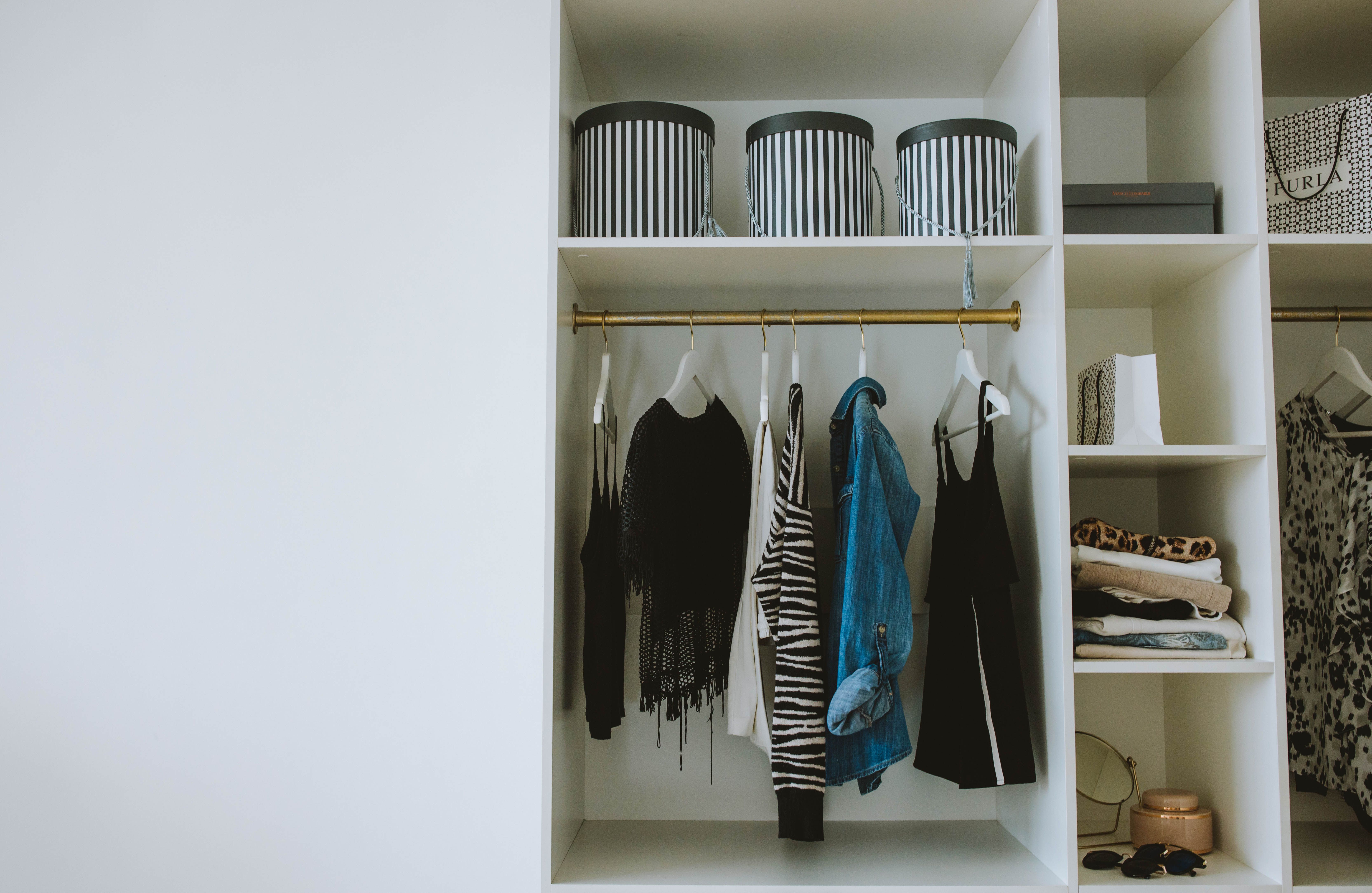 Caixas organizadoras e cabides alinhados dentro de guarda-roupa