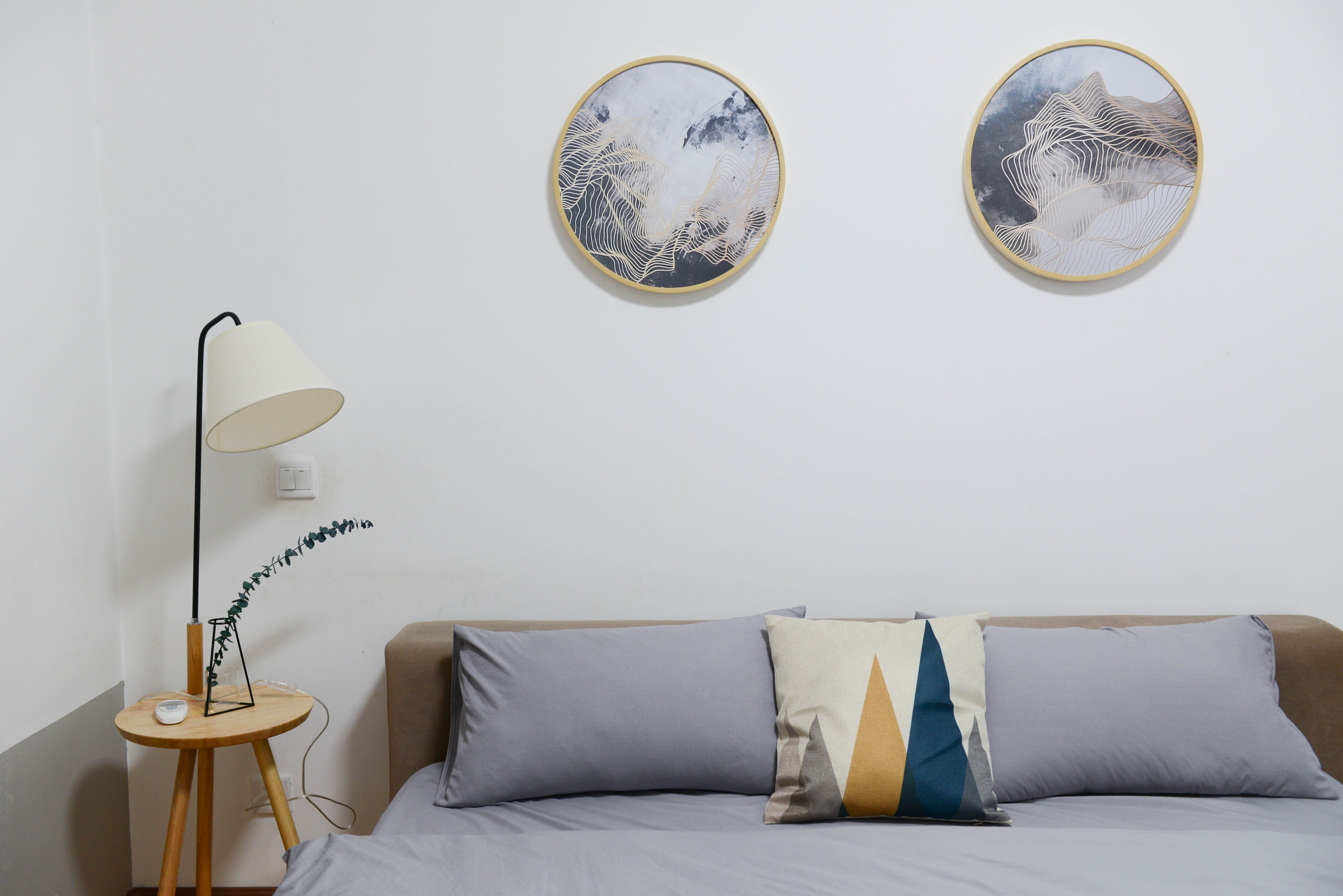 Quarto com quadro decorativo acima da cabeceira e luminária