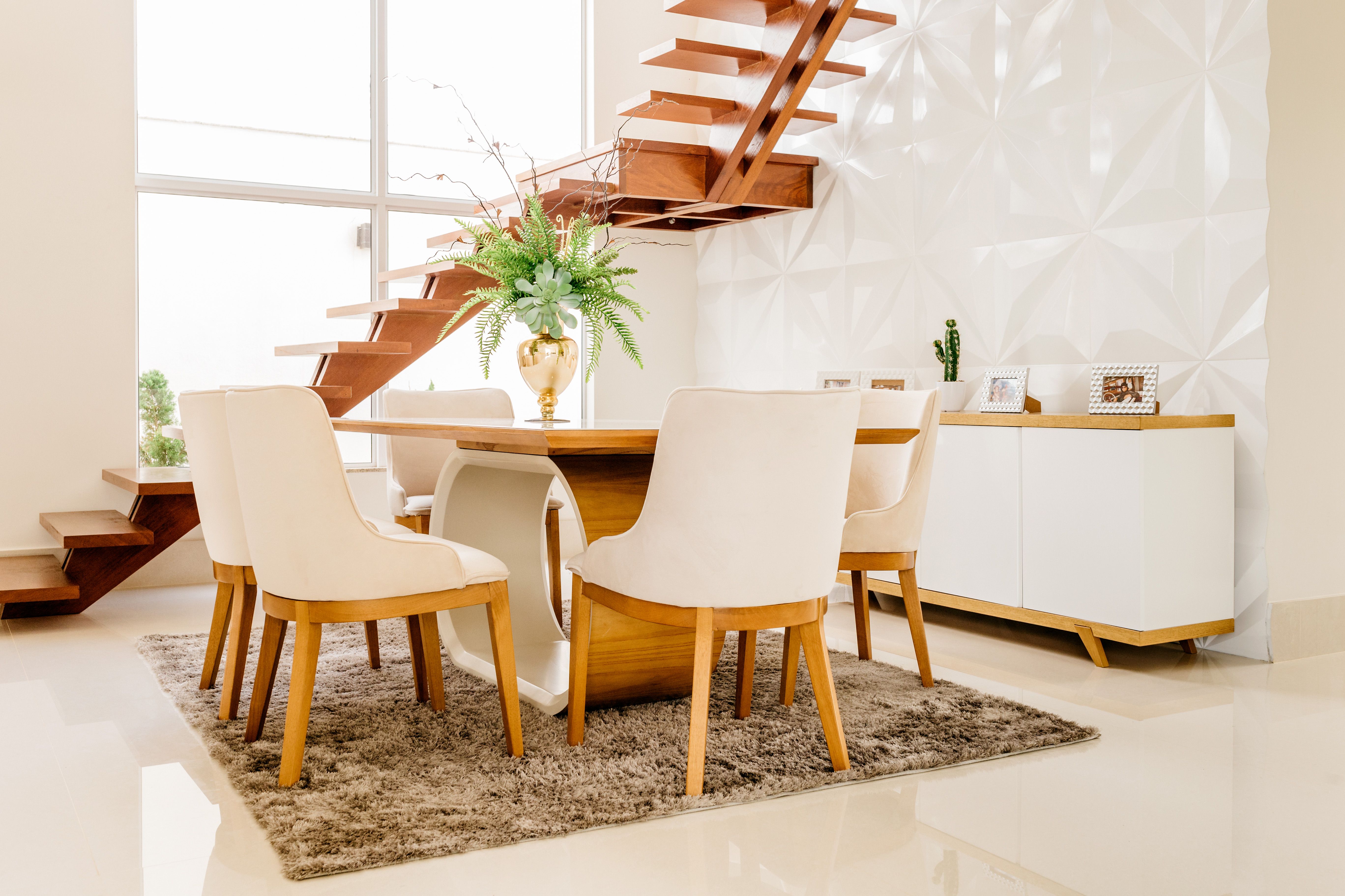 Sala de jantar elegante com escada de madeira e decoração minimalista
