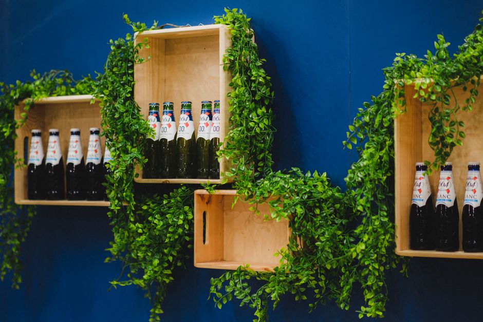 Nicho de parede feito com caixote de madeira segurando livros e plantas