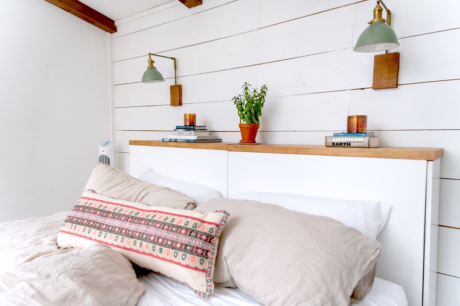 Quarto aconchegante com iluminação de parede substituindo abajur de mesa