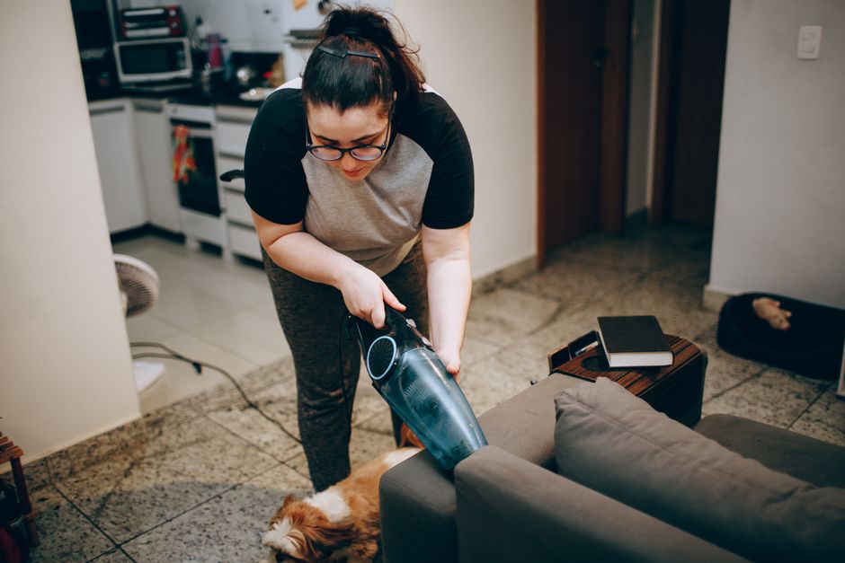 Mulher limpando o sofá com aspirador portátil