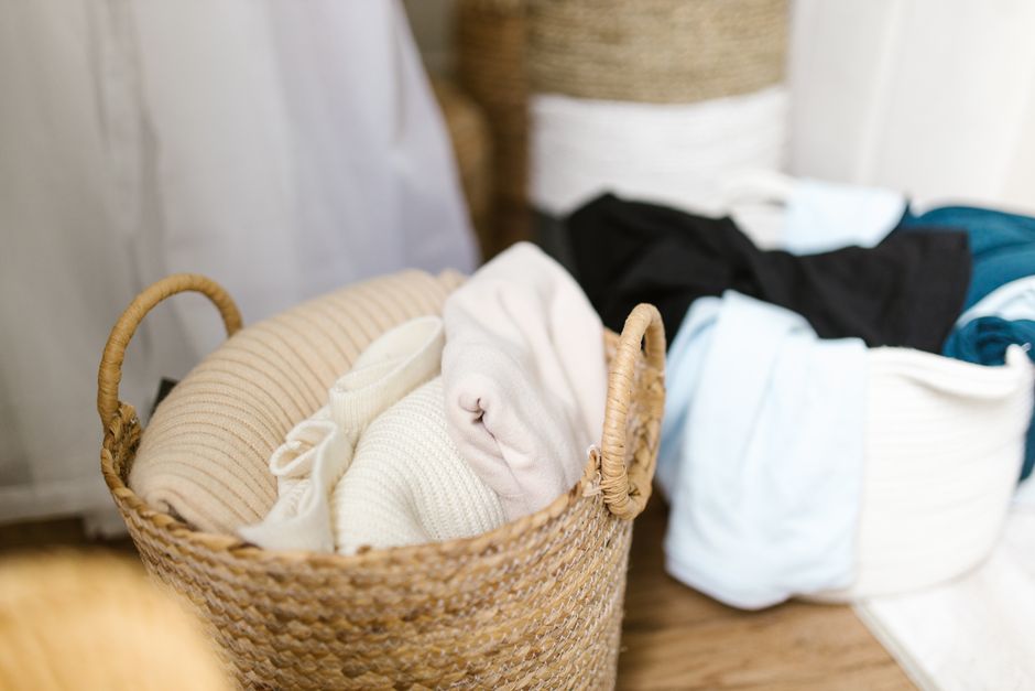 Cesto organizador de tecido com roupas de cama dobradas