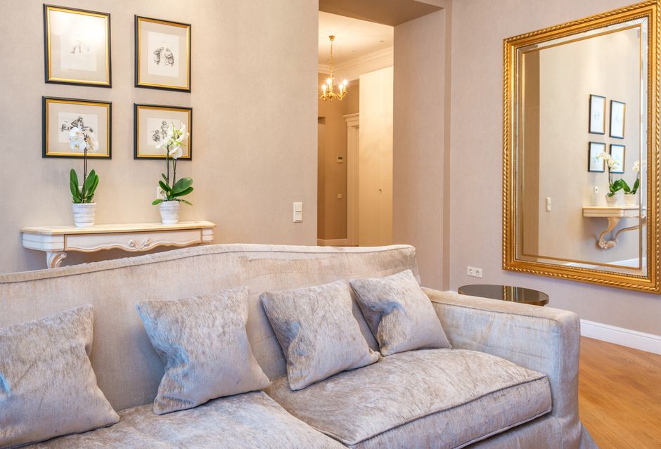 Espelho decorativo com moldura dourada na parede