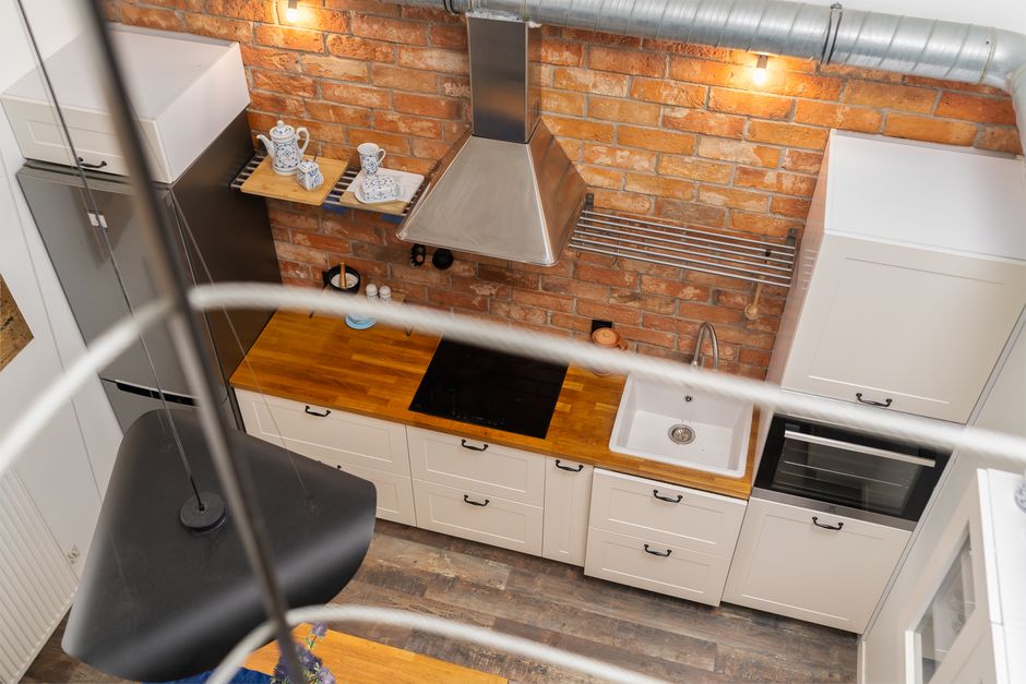 Cozinha contemporânea com parede de tijolo e bancada de madeira