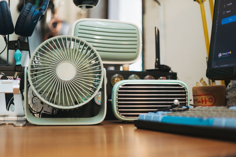 Ventilador portátil sobre mesa de home office ao lado do notebook
