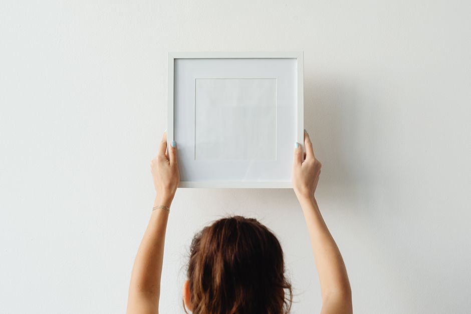 Pessoa pendurando um quadro vazio na parede para planejar o layout