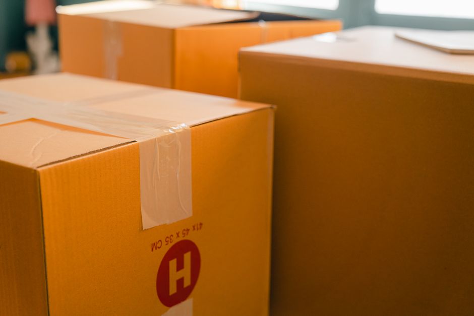 Caixas de papelão empilhadas perto de janela em ambiente iluminado