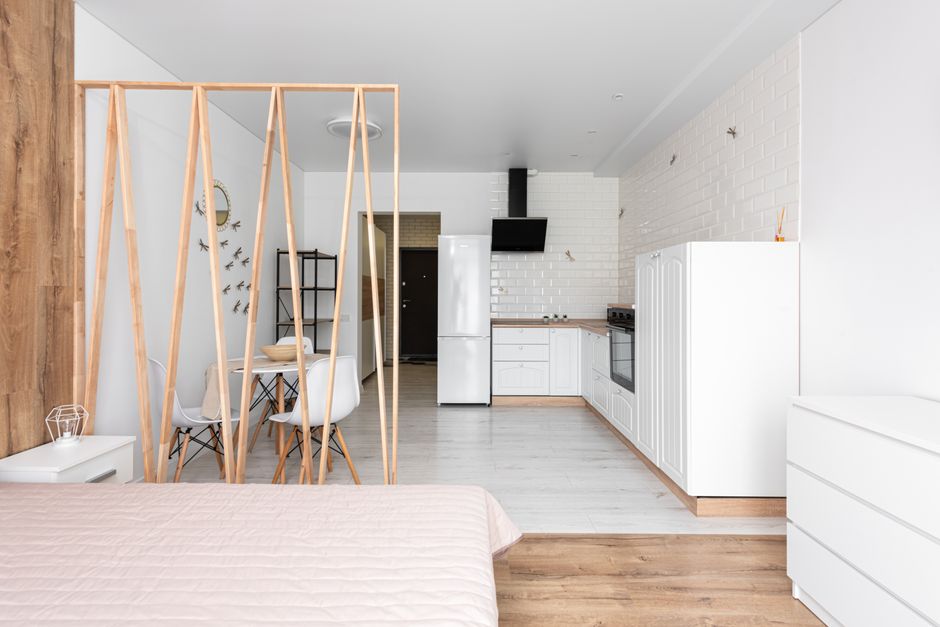 Studio pequeno organizado com ambientes separados por diferentes tipos de divisória