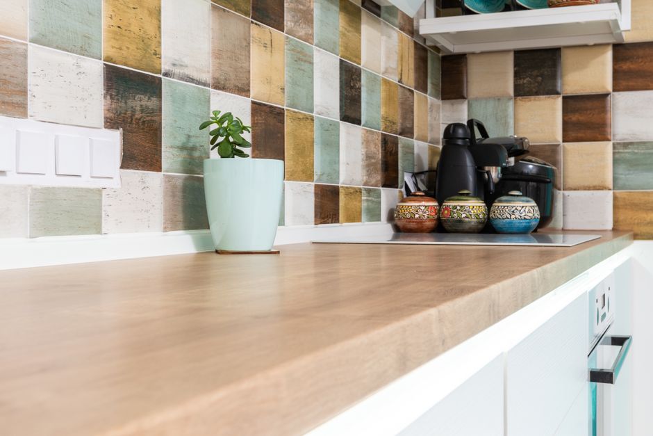 Cozinha com bancada de madeira e azulejos coloridos estampados na parede