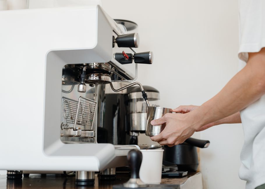 Pessoa operando o painel de uma cafeteira espresso automática na cozinha