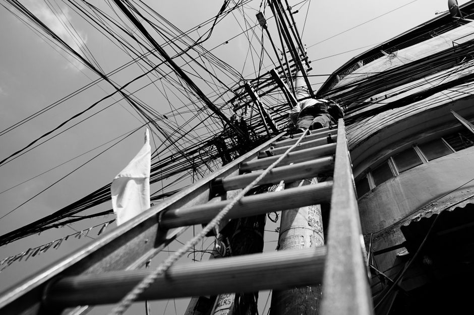 Técnico subindo em escada isolante para mexer em fiação elétrica