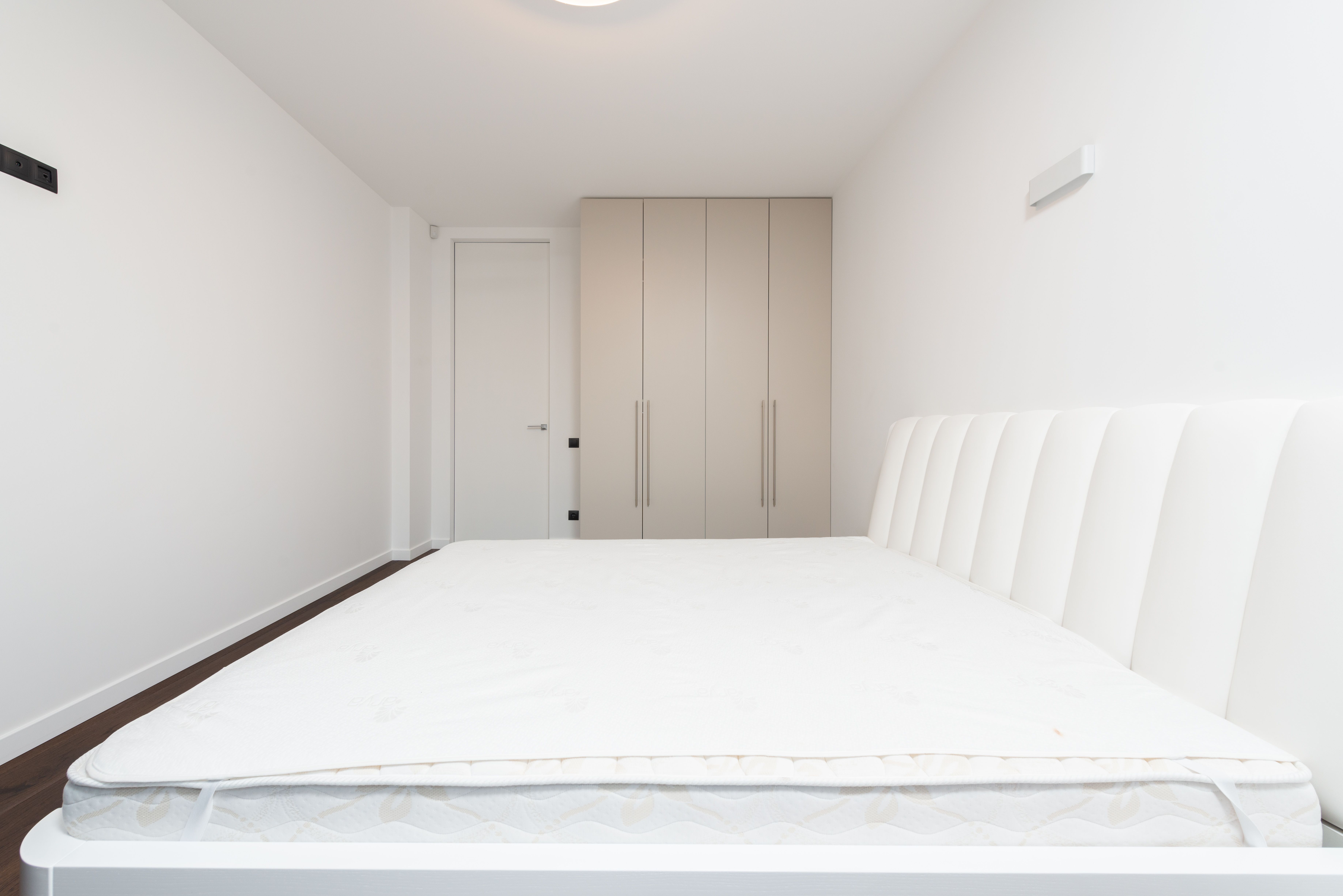 Colchão casal nu sobre estrutura branca de cama, sem lençol, mostrando o volume real do produto