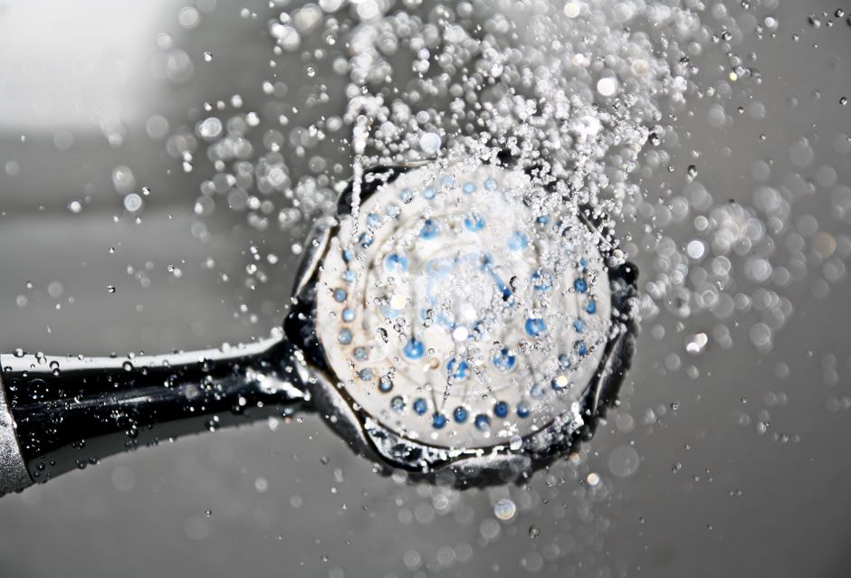 Crivo de chuveiro soltando gotas de água em close