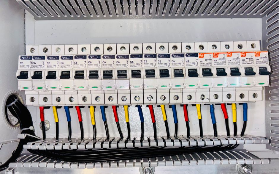 Quadro de disjuntores aberto com fios coloridos organizados