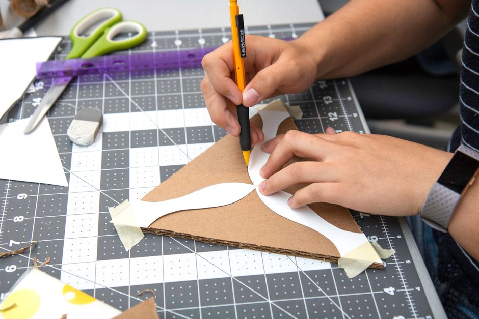 Pessoa cortando papelão sobre base de corte para artesanato