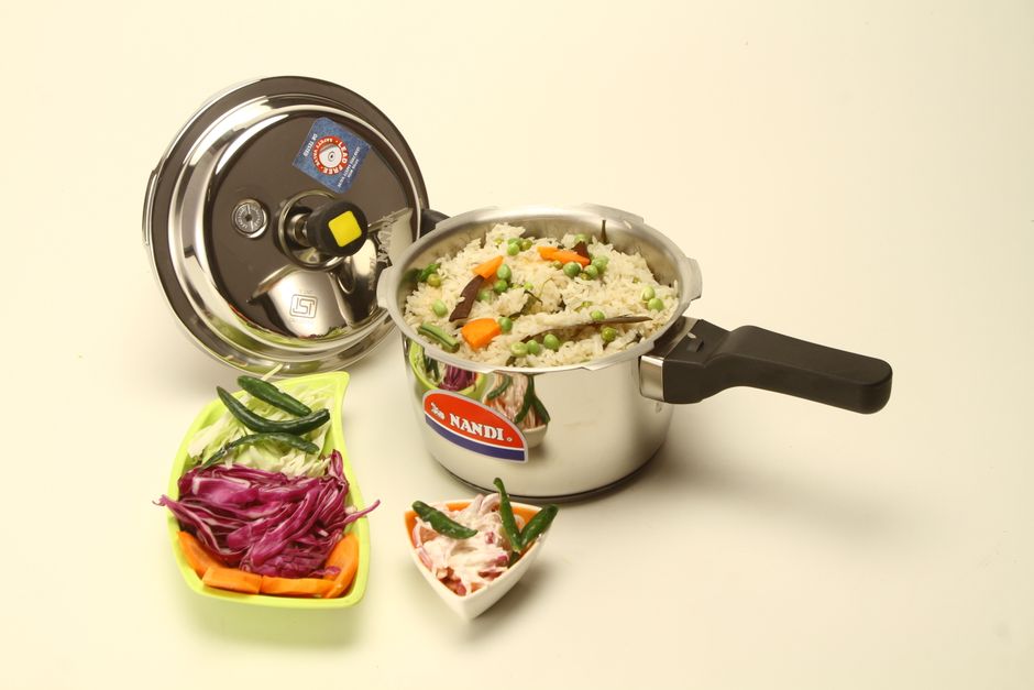 Panela de pressão em aço inox com arroz e vegetais cozidos, pronta pra servir