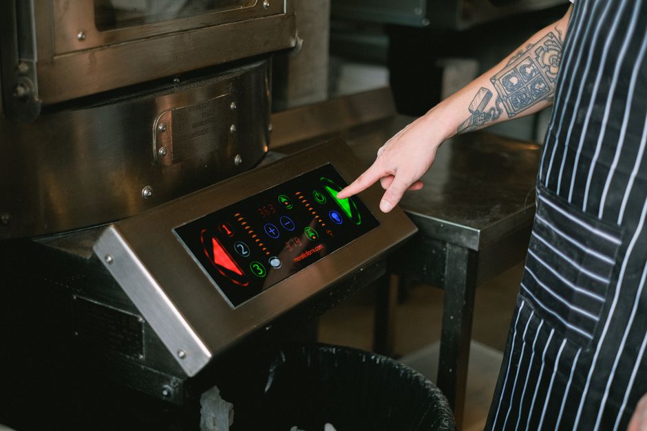 Pessoa operando painel de controle touchscreen em cozinha moderna