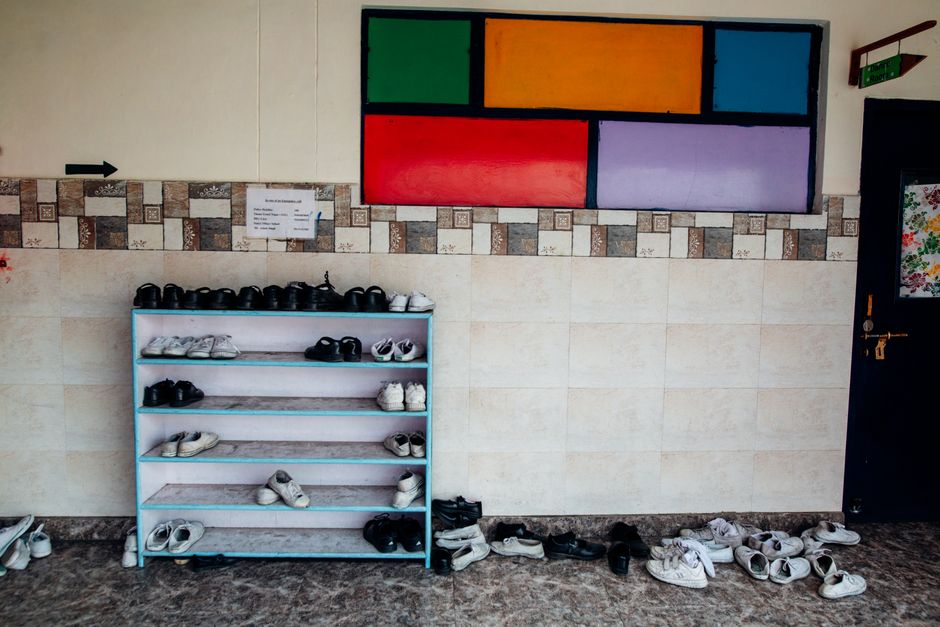 Sapateira de tecido pendurada na porta do armário com pares de sapato organizados em bolsos