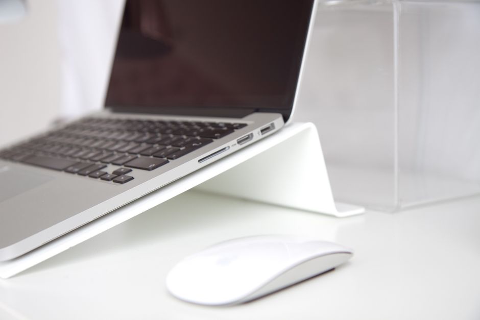 Notebook apoiado sobre suporte dobrável compacto ao lado de um mouse