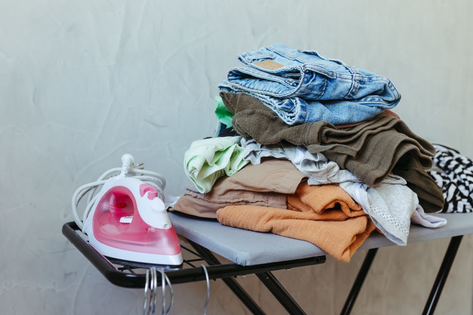 Tábua de passar roupa com peças dobradas ao lado