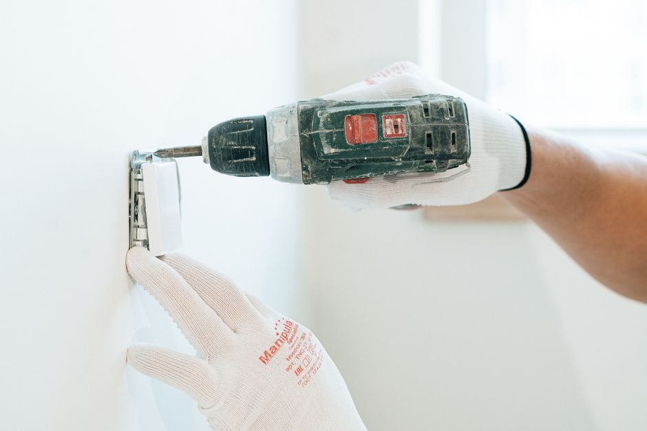 Eletricista instalando ventilador de teto no gancho de suspensão